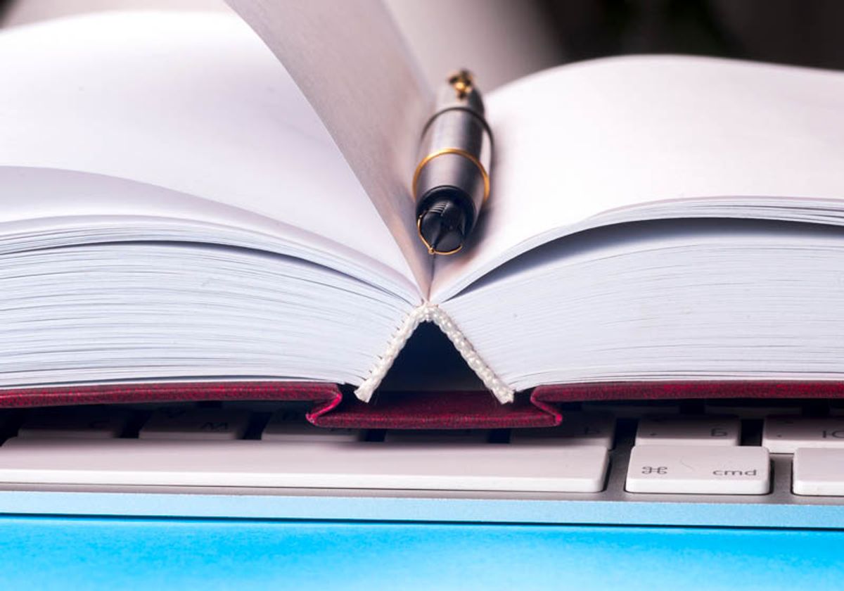 Close up image of an open notebook with blank pages, a computer keyboard, and a pen. Close up image of an open notebook with blank pages, a computer keyboard, and a pen.