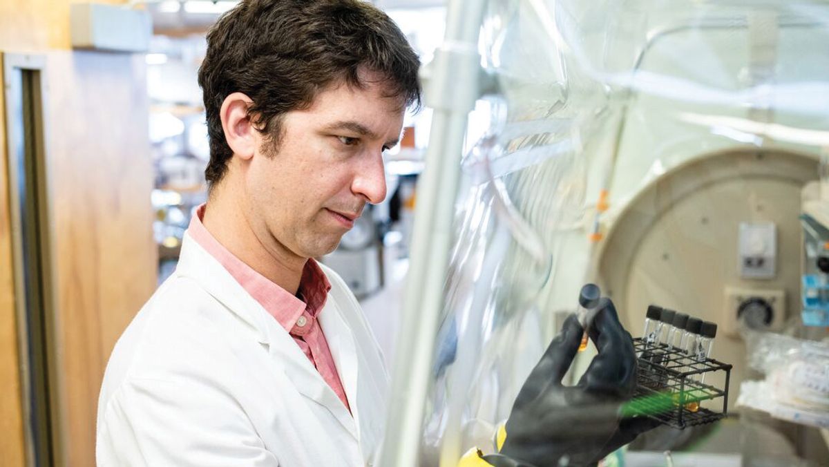 A man wears a laboratory coat. He handles some samples inside a safety laboratory hood. A man wears a laboratory coat. He handles some samples inside a safety laboratory hood.