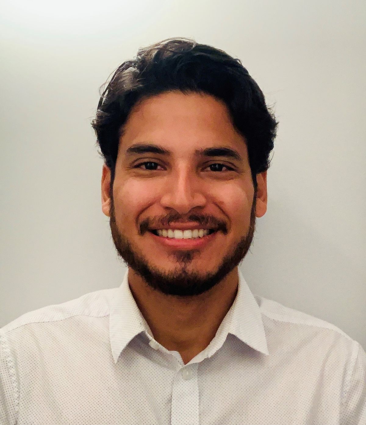 Photograph of Carlo Quintanilla. He is smiling at the camera and wearing a white shirt. Photograph of Carlo Quintanilla. He is smiling at the camera and wearing a white shirt.
