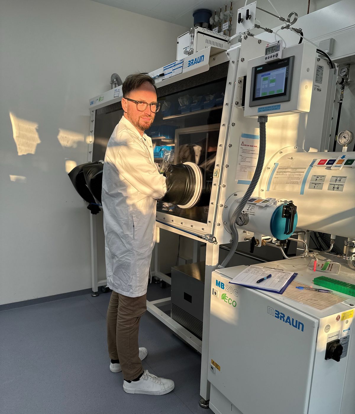 A man wear a laboratory coat. His hands are inside a safety laboratory hood. A man wear a laboratory coat. His hands are inside a safety laboratory hood.