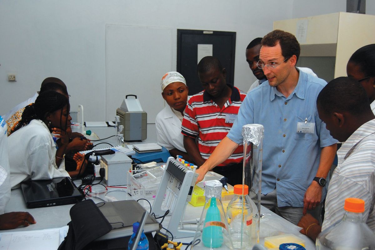 A group of people in a laboratory. Lab equipment is seen on the bench. A group of people in a laboratory. Lab equipment is seen on the bench.