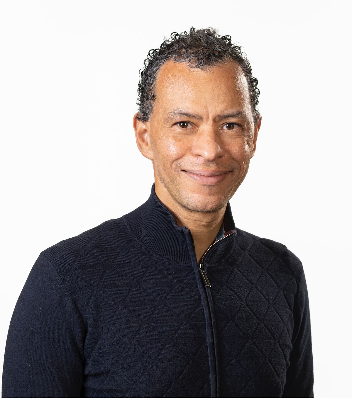 Image of Lloyd Trotman. He wears a navy jacket and smiles at the camera against a white background. Image of Lloyd Trotman. He wears a navy jacket and smiles at the camera against a white background.