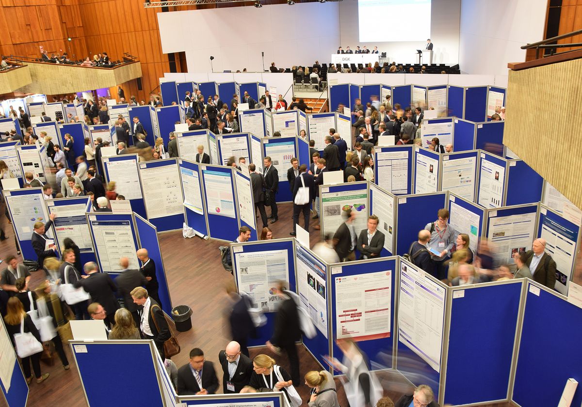 An overhead shot of a busy conference hall filled with posters and presenters. An overhead shot of a busy conference hall filled with posters and presenters.
