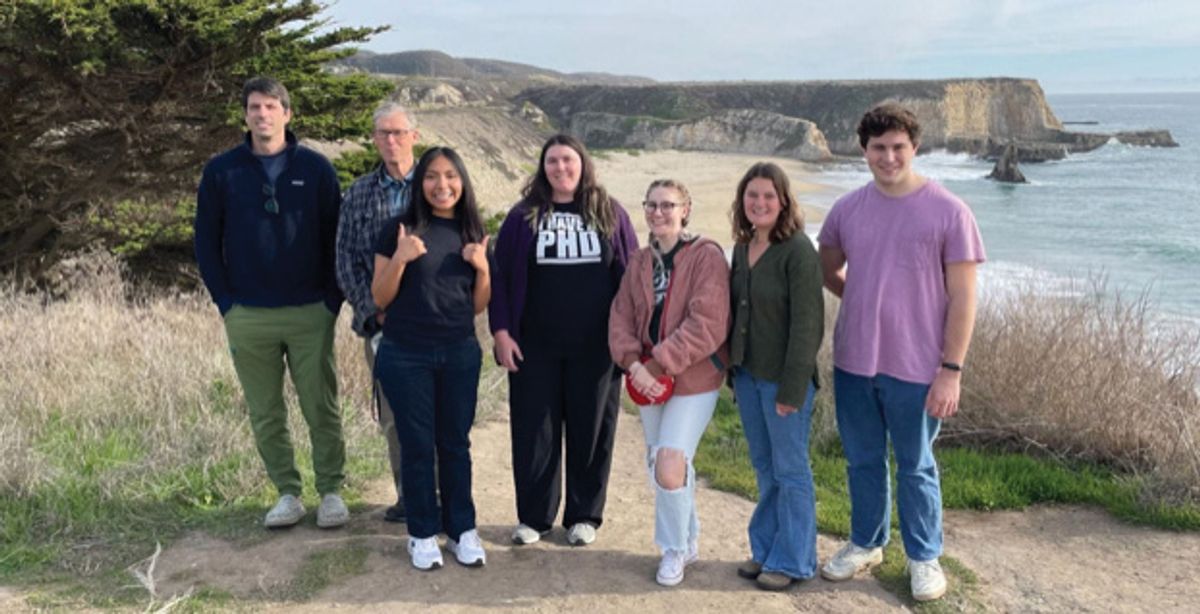 A group of people outside near a beach. A group of people outside near a beach.