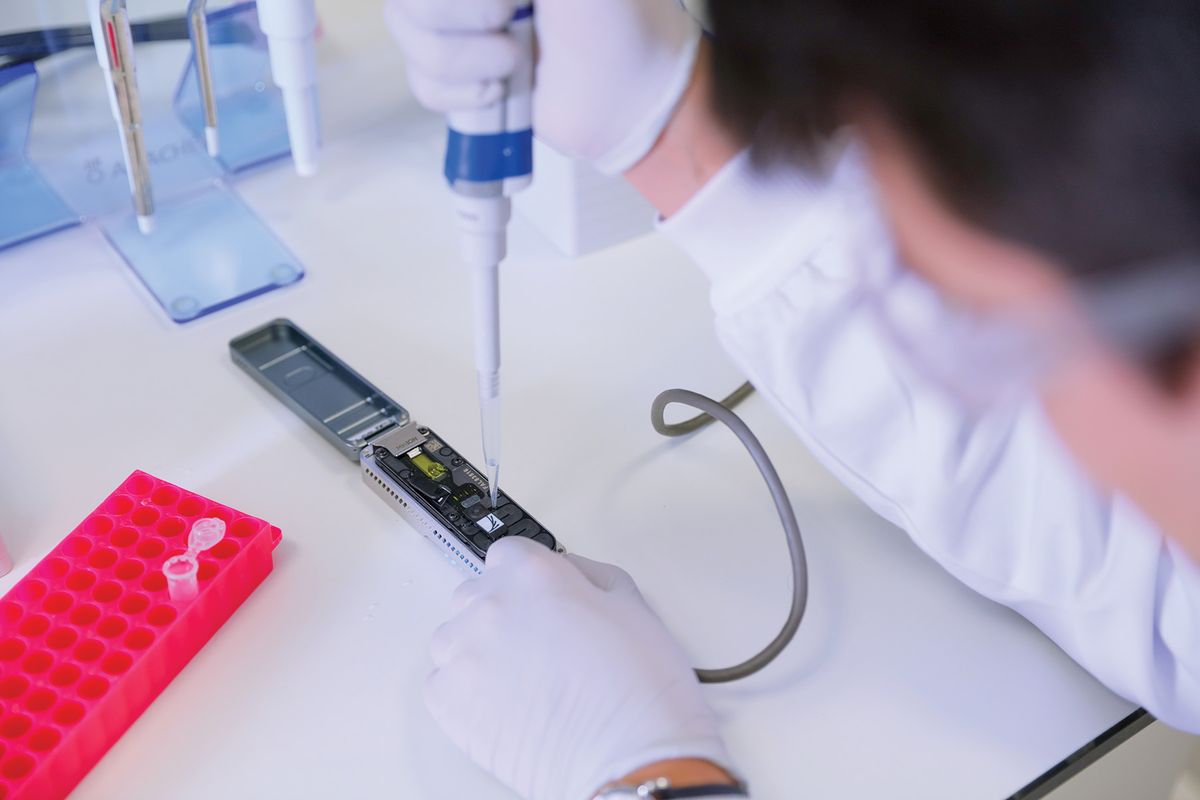 A photo of a scientist loading their prepared library into a flow cell docked within the MinION device. A photo of a scientist loading their prepared library into a flow cell docked within the MinION device.