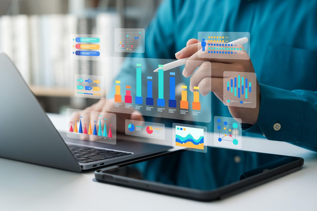 An individual using a laptop and tablet to create and analyze data-based graphics. An individual using a laptop and tablet to create and analyze data-based graphics.